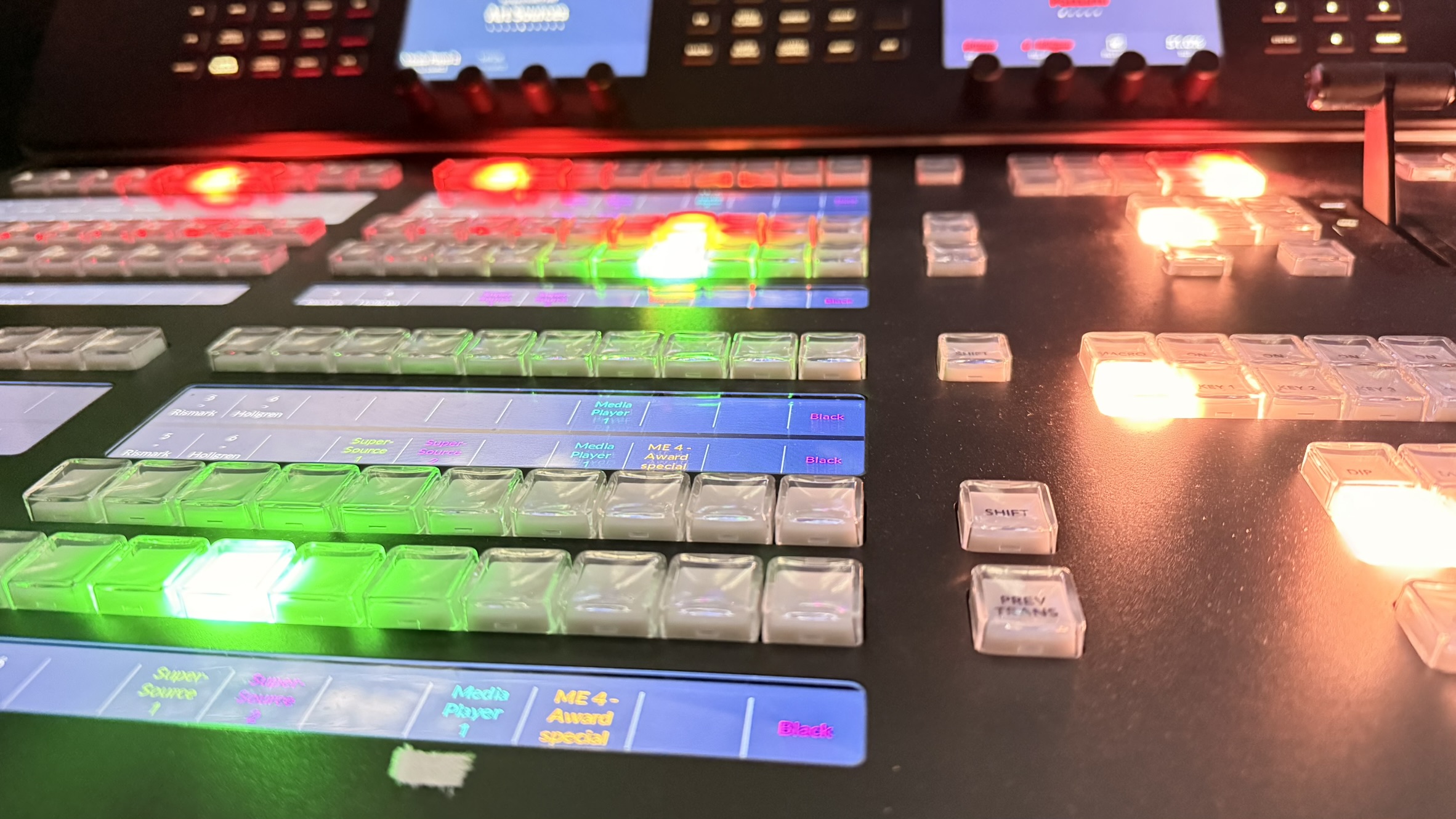 Närbild av en bildmixer med belysta knappar och reglage för TV-produktion